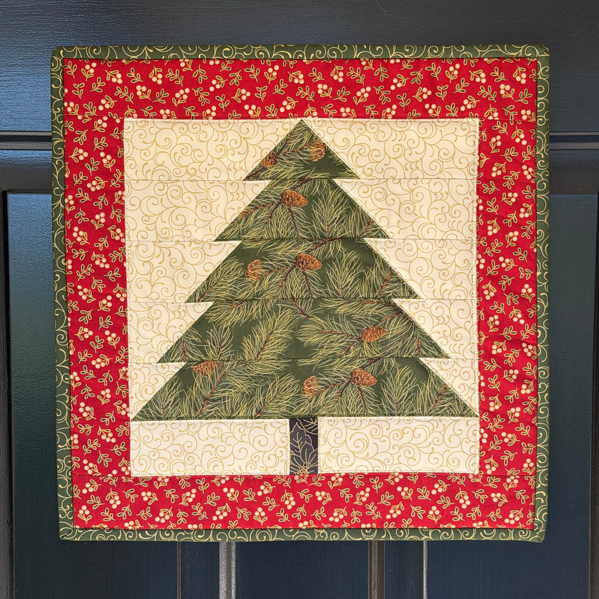 MagneQuilt Evergreen Tree mini quilt with a green pieced tree, cream background, and red holiday border.